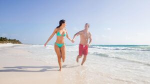 Couple running down a beach holding hands playfully