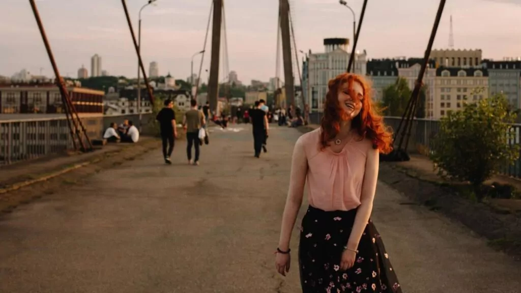 Young cheerful woman walking on bridge in city