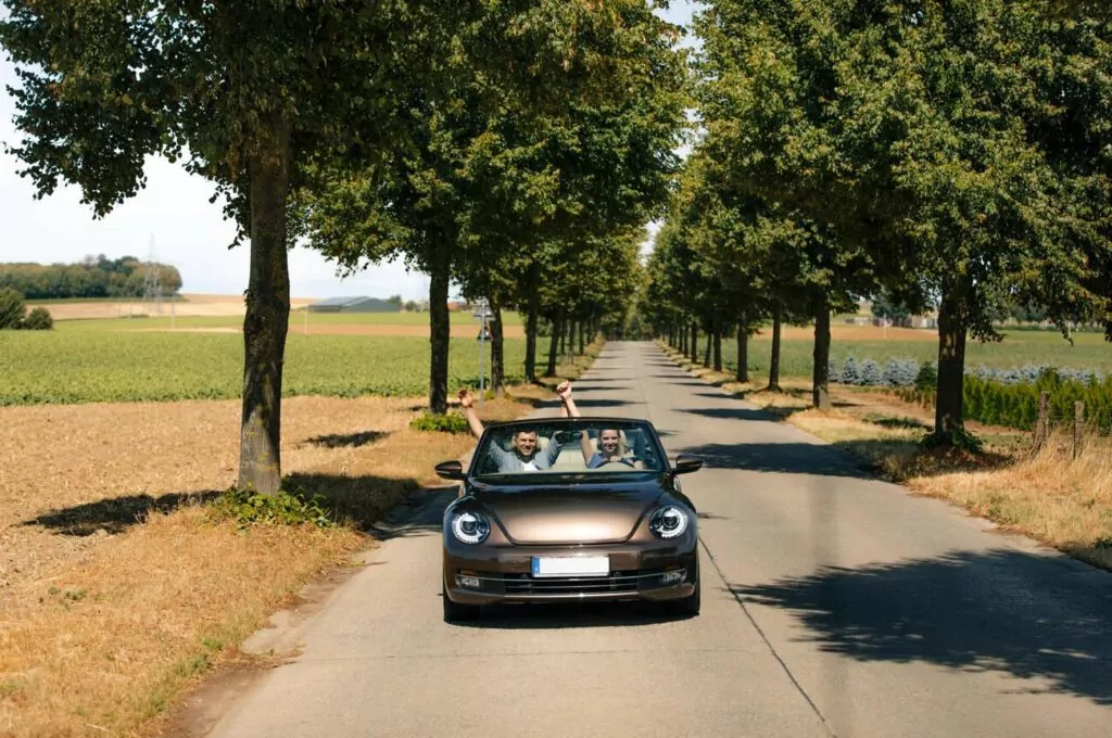 Happy couple driving in convertible car on a country road