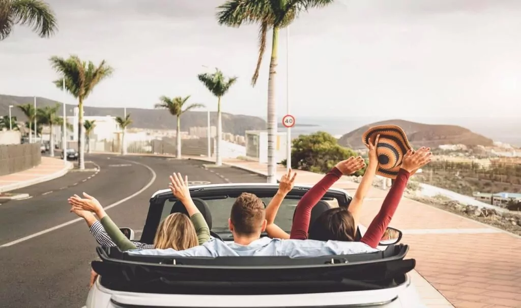 Happy friends having fun in convertible car on vacation