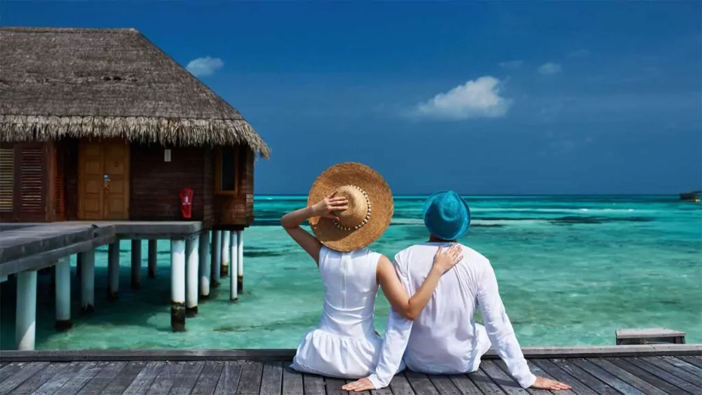 Couple enjoying a tropical vacation, sitting on a deck by the ocean.