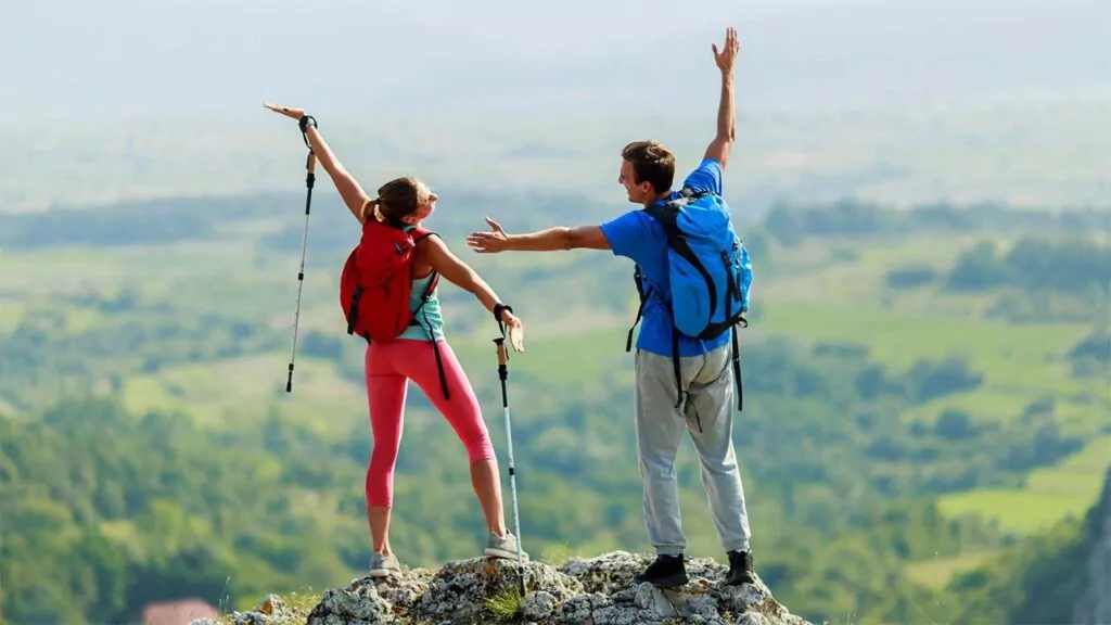 Two hikers celebrating on top of a mountain with scenic views.