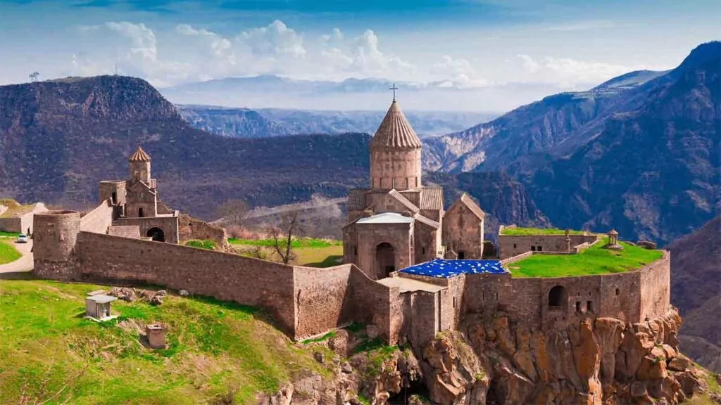 Ancient fortress and church atop a cliff, surrounded by stunning mountain views